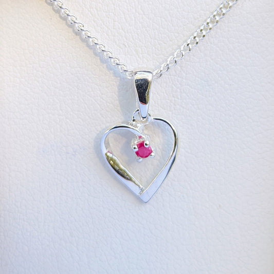 Heart-shaped silver pendant with a pink gemstone on a white background